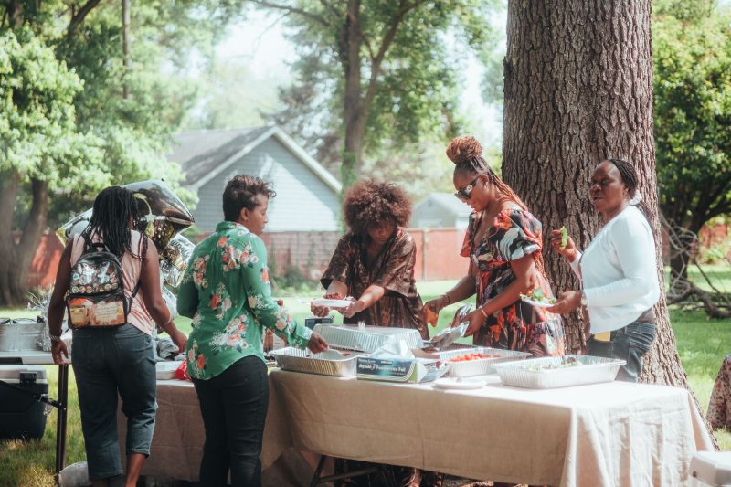 Women enjoying an outdoor buffet at a community gathering, illustrating a welcoming parish fundraiser meal.